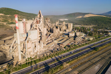 Highway with moving cars and industrial manufacturing cement factory, aerial view