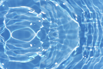 Blue water with ripples on the surface. Defocus blurred transparent blue colored clear calm water surface texture with splashes and bubbles. Water waves with shining pattern texture background.