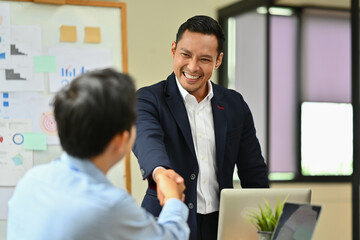Confident businessman shaking hands with partner after closing deal or successful negotiations at meeting