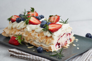 Strawberry meringue pavlova roll with cream and fresh seasonal berries