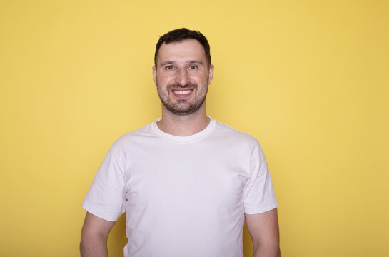 Young smiling happy satisfied cheerful caucasian man casual clothes looking camera with toothy smile isolated on yellow background studio portrait. Lifestyle concept. 