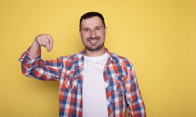 Portrait of excited young man holding something invisible in hand. Positive male showing empty mockup place for ad, banner. 