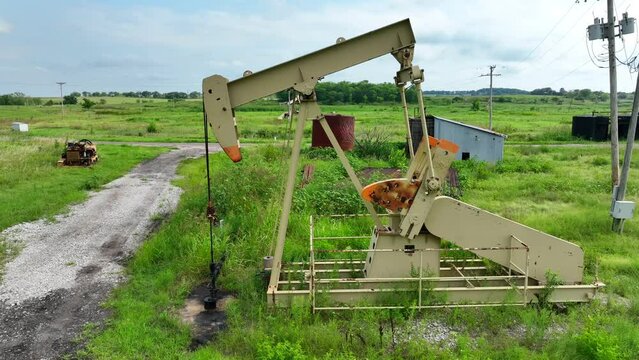Oil well in rural USA. Aerial shot of pump in motion with holding tanks in the background.