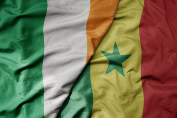 big waving national colorful flag of ireland and national flag of senegal .