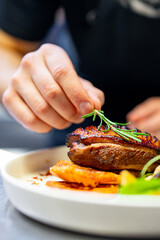 chef hand cooking Roasted Duck breast fillets with vegetable salad and batat in plate on restaurant kitchen