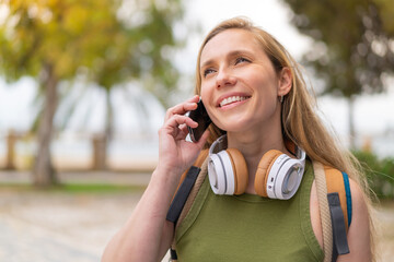 Young blonde woman at outdoors using mobile phone