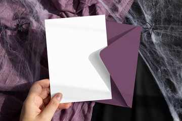 Halloween 5x7 card mockup in hand with purple envelope on black background 