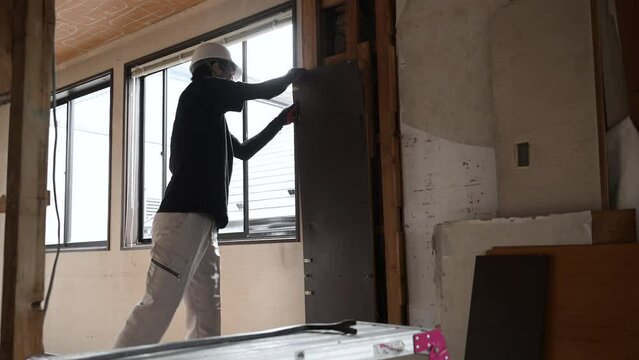 Young masked worker at construction site Video of demolition of interior Breaking wall with crowbar