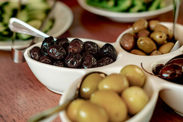 turkish breakfast table served, white dishes, wooden table, black and green olives, oily, fresh