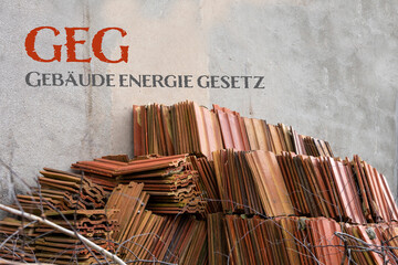 Old roof tiles leaning against a house wall during renovation for the German Gebaeudeenergiegesetz...