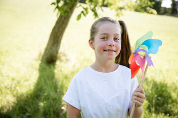 pretty young girl with colorful pinwheel outdoor in green nature