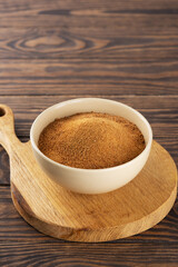 Bowl with unrefined cane sugar Panela on wooden board.