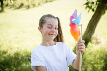 pretty young girl with colorful pinwheel outdoor in green nature