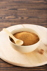 Brown unrefined cane sugar Panela in a bowl on a wooden board.