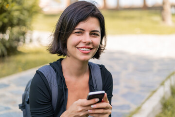 Young pretty Bulgarian woman at outdoors using mobile phone