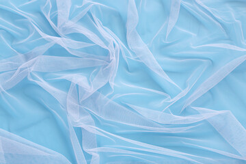 Wavy pattern of bright tulle fabric on soft colorful blue background. Abstract light chiffon, clean...