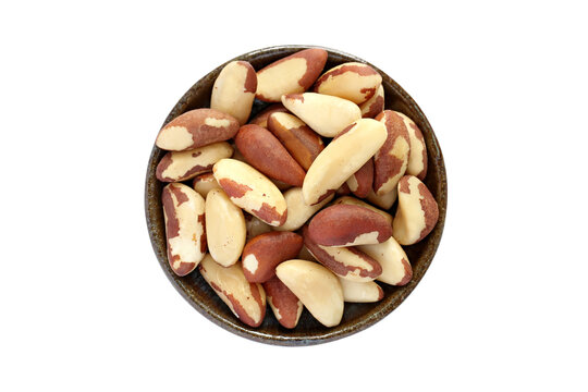 Close up of raw Brazil nuts in brown bowl isolated on white background. Many delicious seeds with nutshell removed, top view