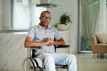 Fototapeta na wymiar Portrait of Black man in glasses sitting in wheelchair at home