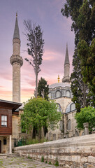 16th century Atik Valide Mosque, surrounded by tall lush trees, located in Uskudar district, Istanbul, Turkey. The photo captures the beauty of the mosque's architecture, with its towering minarets