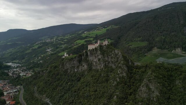 Klausen, Italy - 4K flying above Saben Abbey (Monastero di Sabiona) by Chiusa (Klausen) commune northeast of the city of Bolzano and South Tyrol Dolomites at the background on a cloudy summer day