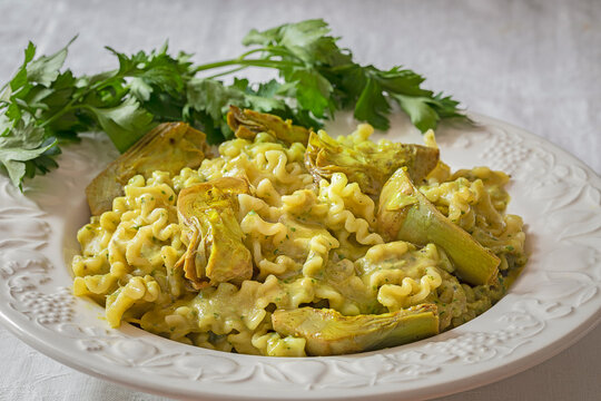 A dish with pasta with artichokes and parsley.