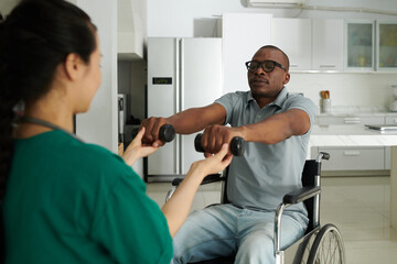 Physiotherapist working with patient asking him to lift dumbbells