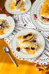 Homemade cherry strudel cut into slices on white porcelain plates on lace tablecloth