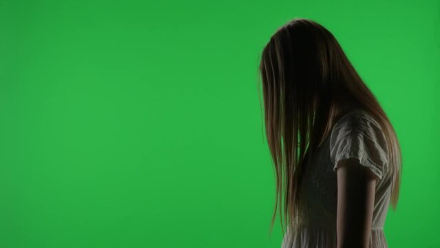 Medium side view green screen, chroma key video of a posessed female figure, ghost, poltergeist, zombie pulling her hands out. Hair is covering her face. Chroma key.