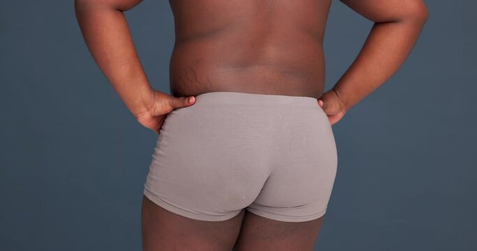 Back, buttocks in underwear and a dance for beauty with a man in studio on a grey background. Health, freedom and a model moving in underpants for natural skincare or body positive freedom closeup