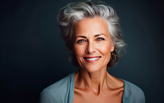 Beautiful mid age woman studio portrait over dark grey background.