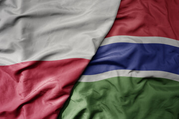 big waving national colorful flag of poland and national flag of gambia .