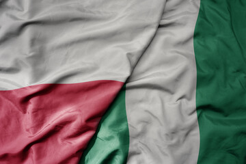 big waving national colorful flag of poland and national flag of nigeria .