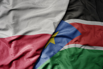Fototapeta premium big waving national colorful flag of poland and national flag of south sudan .