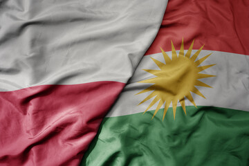 big waving national colorful flag of poland and national flag of kurdistan .