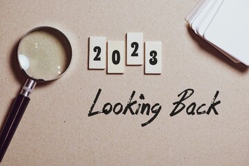 The inscrption 2023 looking back on brown background on desk. The year highlights, best events,...