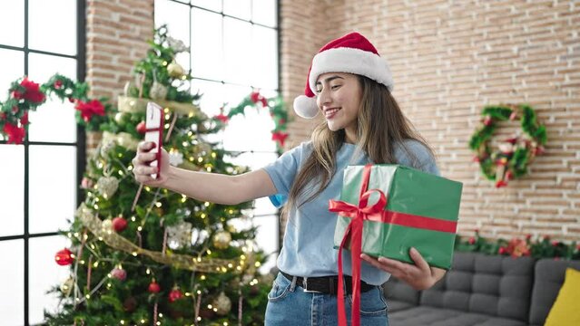 Young beautiful hispanic woman make selfie by smartphone celebrating christmas at home