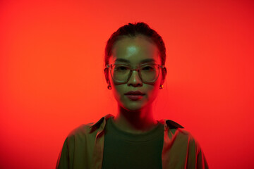Portrait of serious young hacker standing in red light and looking at camera