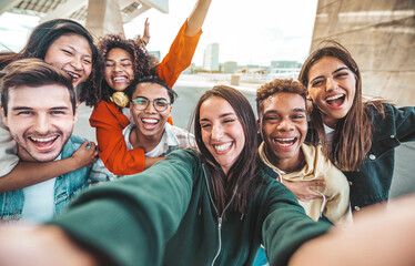 Multiracial young people laughing together at camera - Happy group of friends having fun taking selfie pic with smart mobile phone - Youth community concept with guys and girls hugging outdoors - obrazy, fototapety, plakaty