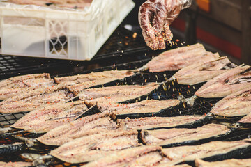 Flavouring fresh mackerel fish in a mobile smokehouse in a farmer's street market in Vilnius,...