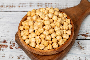 Roasted hazelnuts in wood bowl. Peeled hazelnuts kernel on white wood background