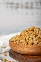 Dried mulberries in wooden bowl. Sun-dried mulberry on a white wood background. Close up