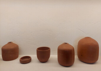 Series of pottery display made of clay, in white stucco wall finishes and textured white paint ledges, open niche of ceramic pots, display.