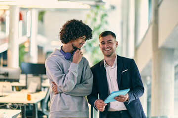 In a modern office setting, an African American businessman engages in a discussion with his director, using a tablet to address business challenges, symbolizing collaboration and technology