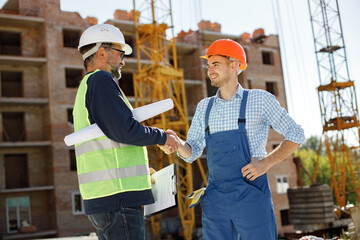 Two men engineers at a construction site are looking at the drawings