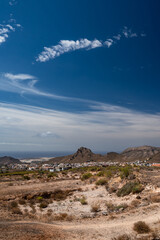 Hiking trail in a desert with a view of a city, sea or ocean and mountains