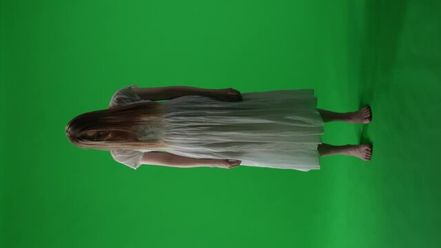Full-size vertical green screen, chroma key video of a posessed female, woman figure, ghost, poltergeist, zombie pulling her hands out to the camera. Hair is covering her face. Chroma key.