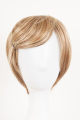 Natural looking blonde fair wig on white mannequin head. Short hair cut on the plastic wig holder isolated on white background, front view.