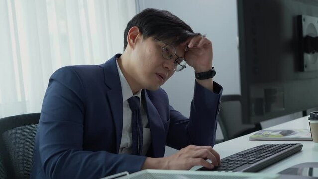 serious asian business man using computer on desk in office