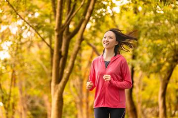 紅葉の中でジョギングをする若い女性