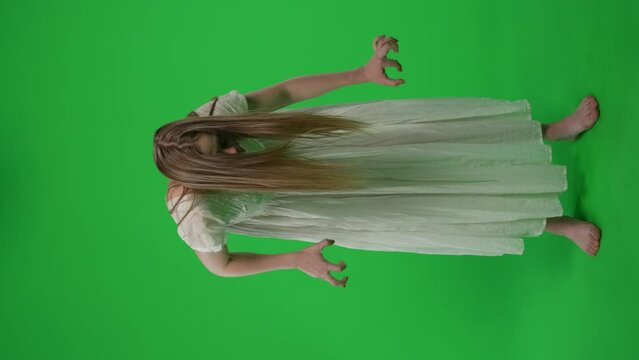 Full-size vertical green screen, chroma key video of a posessed female, woman figure, ghost, poltergeist, zombie moving in an abrupt, convulsive manner. Hair is covering her face. Chroma key.